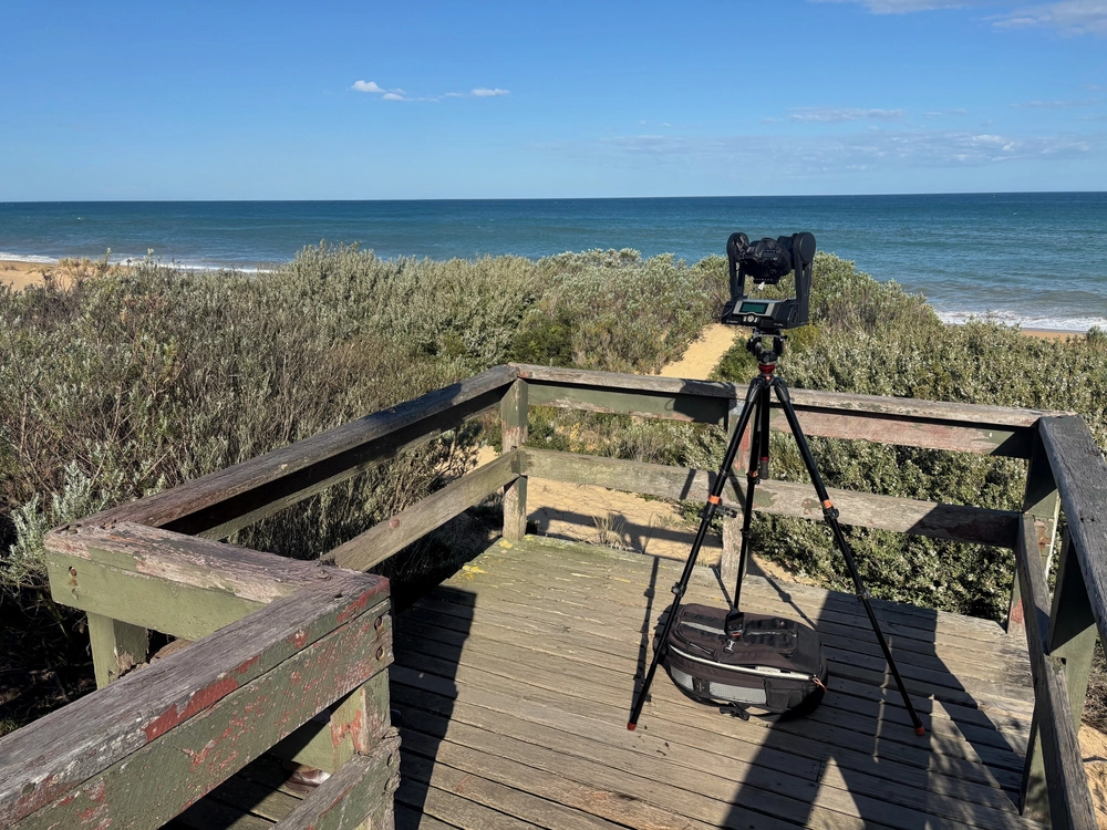 Camera on tripod on wooden platform overlooking beach and ocean